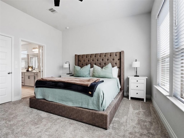 carpeted bedroom featuring a ceiling fan, visible vents, connected bathroom, and baseboards