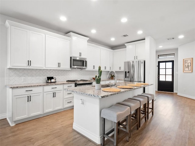 kitchen featuring appliances with stainless steel finishes, light wood-type flooring, a sink, and visible vents