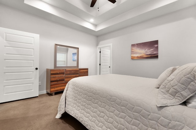 carpeted bedroom with a raised ceiling and ceiling fan