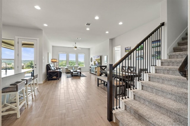 staircase with hardwood / wood-style floors and ceiling fan