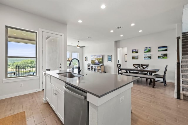 kitchen with sink, white cabinetry, light hardwood / wood-style floors, a center island with sink, and stainless steel dishwasher