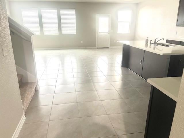 kitchen with sink, light tile patterned floors, and a kitchen island with sink