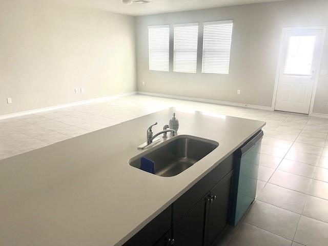 kitchen featuring a healthy amount of sunlight, sink, light tile patterned floors, and dishwasher