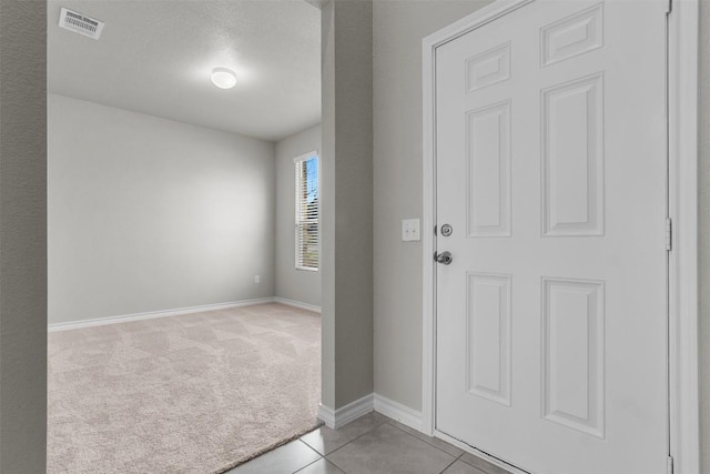 foyer entrance with light colored carpet and a textured ceiling