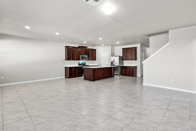 kitchen featuring dark brown cabinets, a center island, a textured ceiling, and appliances with stainless steel finishes