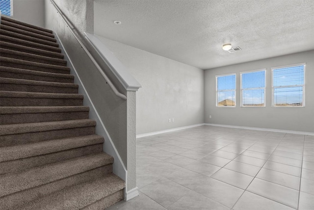 staircase featuring tile patterned flooring and a textured ceiling