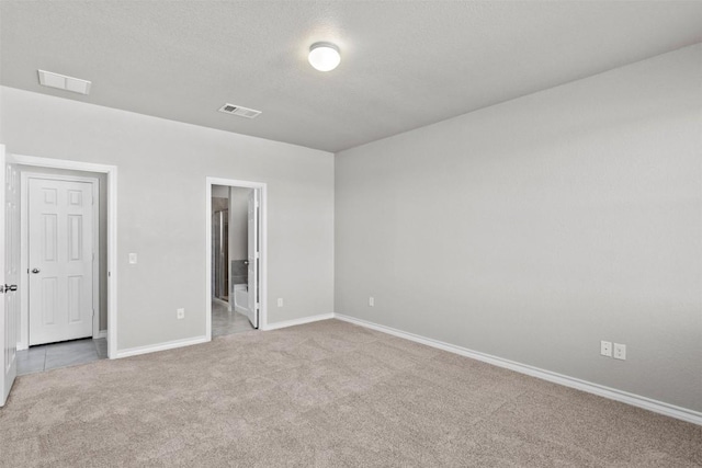 interior space with light colored carpet, connected bathroom, and a textured ceiling