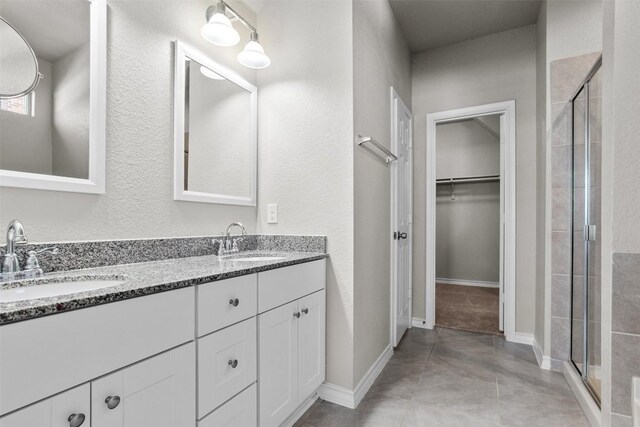 bathroom with an enclosed shower, vanity, and tile patterned flooring