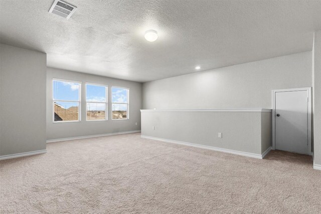 empty room featuring light colored carpet and a textured ceiling