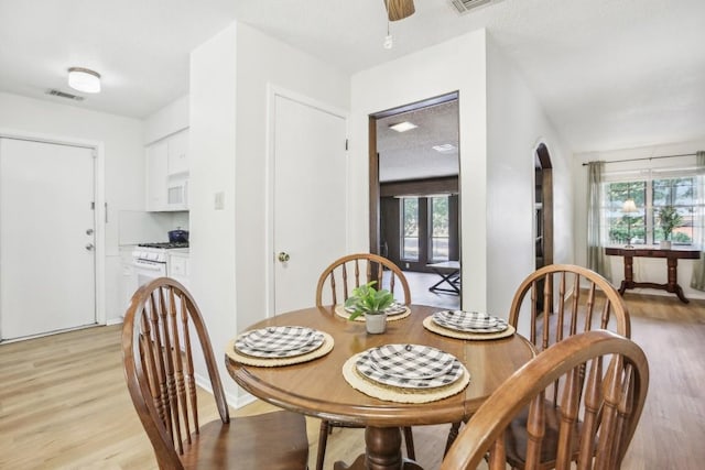 dining area with ceiling fan, light hardwood / wood-style floors, and a textured ceiling