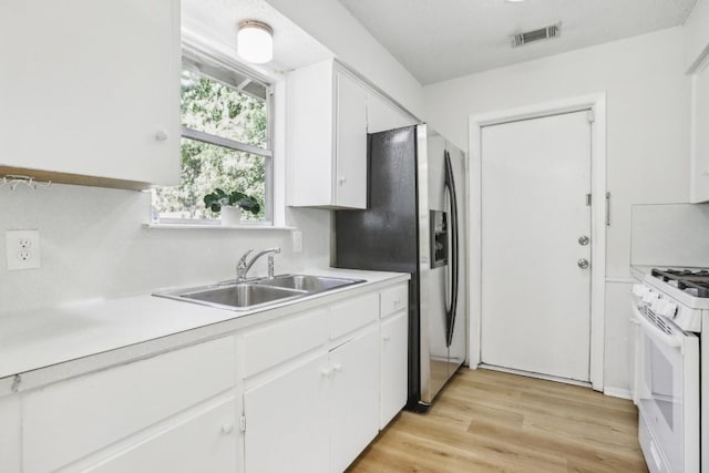 kitchen with white cabinetry, sink, white gas range oven, and stainless steel refrigerator with ice dispenser