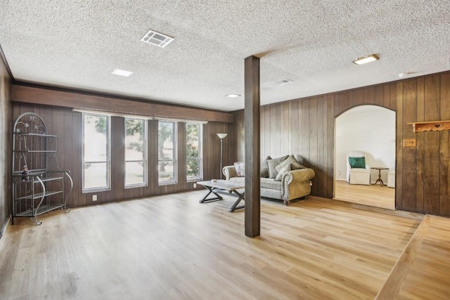 living room with hardwood / wood-style floors, a textured ceiling, and wood walls