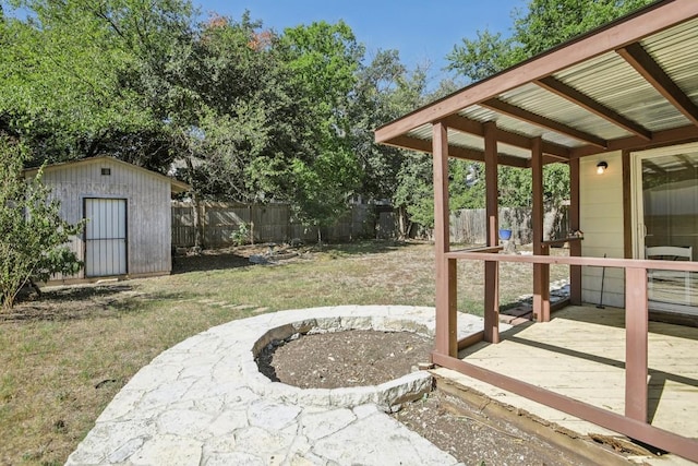 view of yard featuring a storage shed, an outdoor fire pit, and a deck