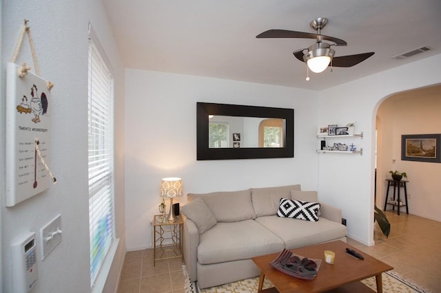 tiled living room with a wealth of natural light and ceiling fan