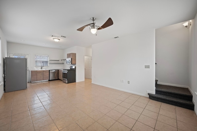 interior space featuring stainless steel appliances, light tile patterned flooring, sink, and ceiling fan