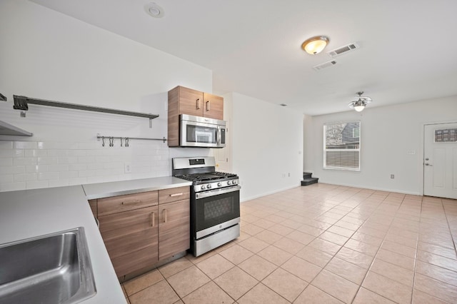 kitchen featuring sink, decorative backsplash, stainless steel appliances, and light tile patterned flooring