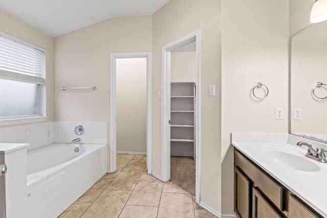 bathroom with tile patterned flooring, vaulted ceiling, a bath, and vanity