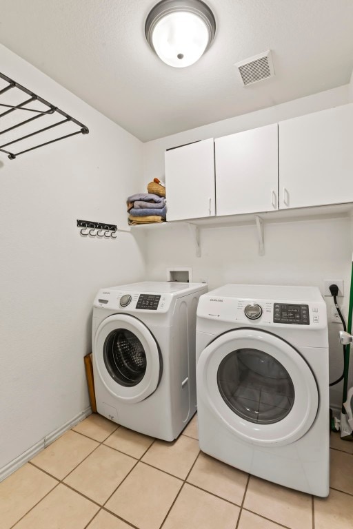 laundry room with cabinets, washing machine and dryer, and light tile patterned flooring