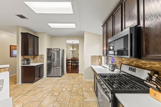 kitchen featuring appliances with stainless steel finishes, an inviting chandelier, backsplash, and dark brown cabinetry