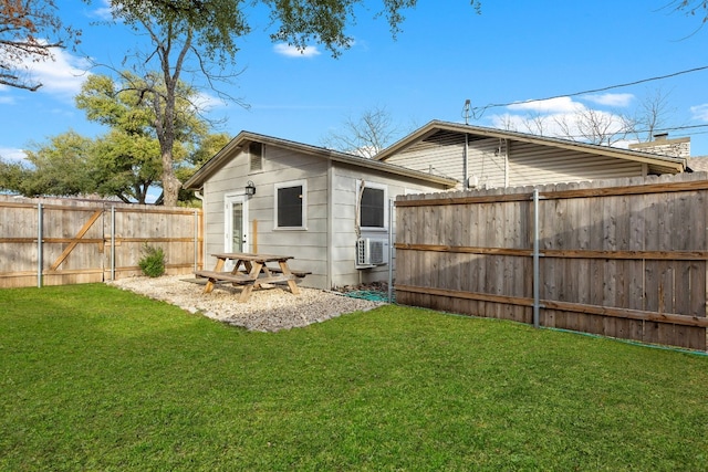 rear view of house with a fenced backyard, a lawn, and an outbuilding