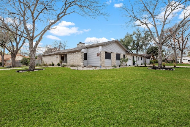 view of side of home with a yard, brick siding, and a chimney