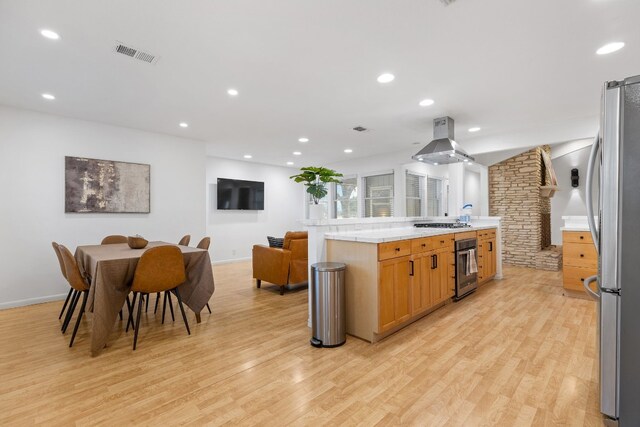 kitchen with island exhaust hood, stainless steel appliances, and light wood-type flooring