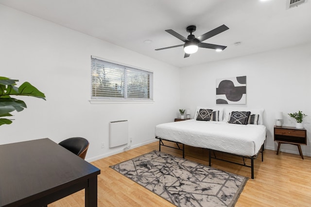 bedroom featuring hardwood / wood-style flooring, ceiling fan, and heating unit