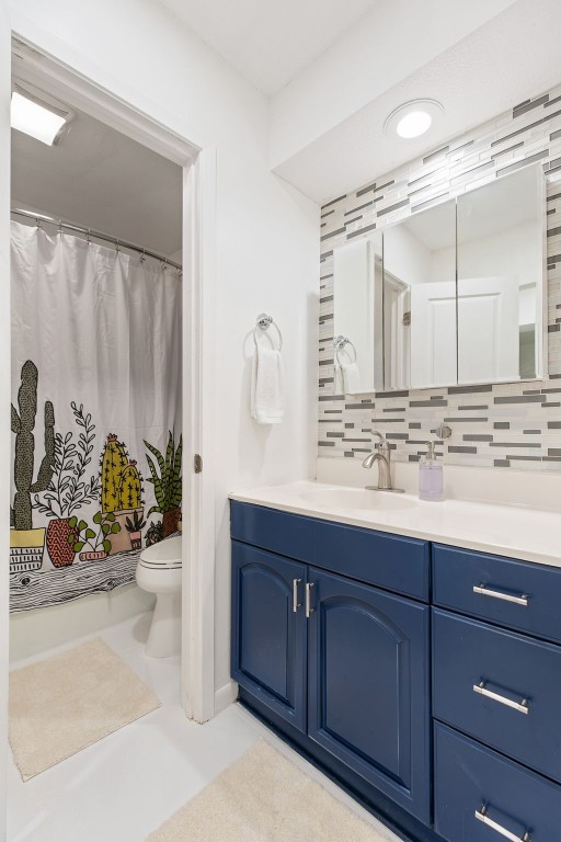 full bath featuring tasteful backsplash, vanity, and toilet