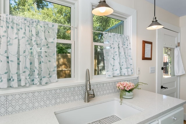 interior space featuring hanging light fixtures, sink, and light stone counters