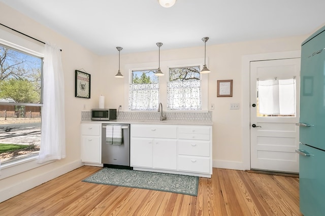 kitchen featuring stainless steel appliances, light hardwood / wood-style flooring, white cabinets, and decorative light fixtures