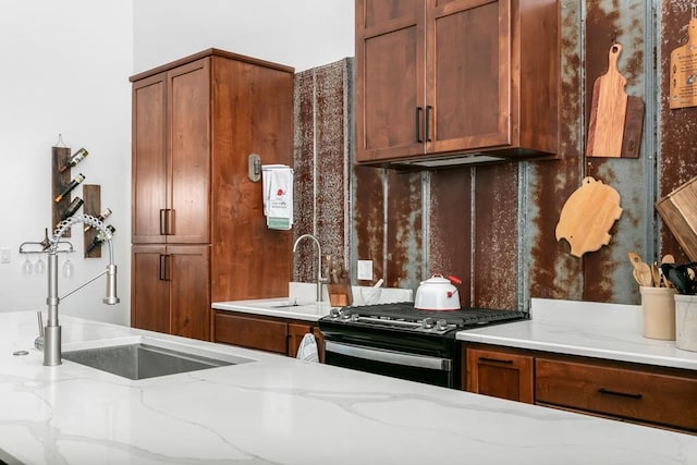 kitchen with light stone counters, sink, and black range with gas cooktop