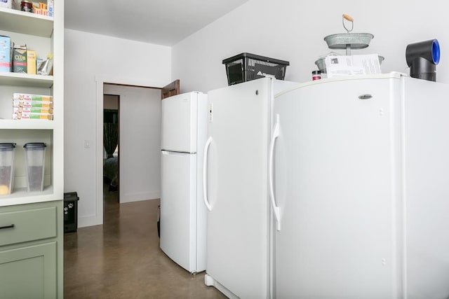 kitchen with white refrigerator and green cabinetry