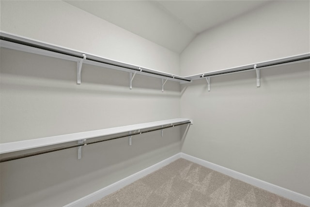 spacious closet with lofted ceiling and light carpet