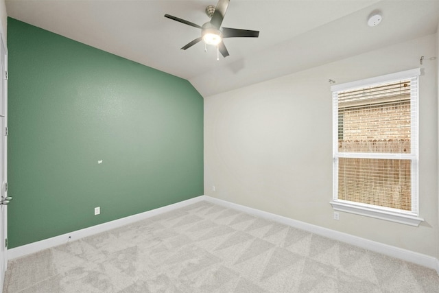 spare room with vaulted ceiling, light colored carpet, and ceiling fan