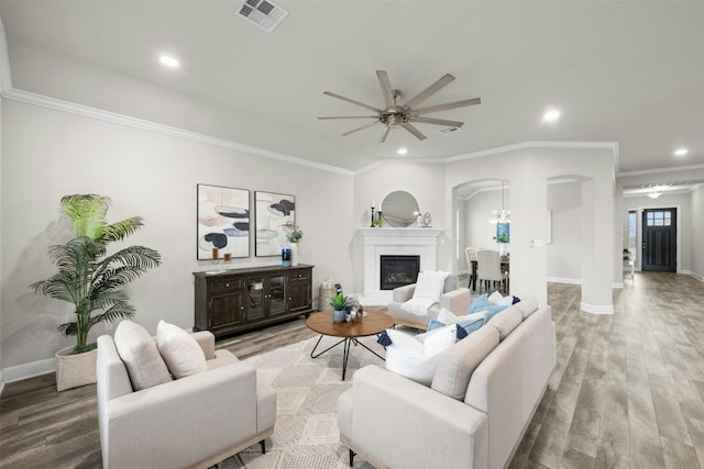 living room featuring ceiling fan, ornamental molding, and light wood-type flooring