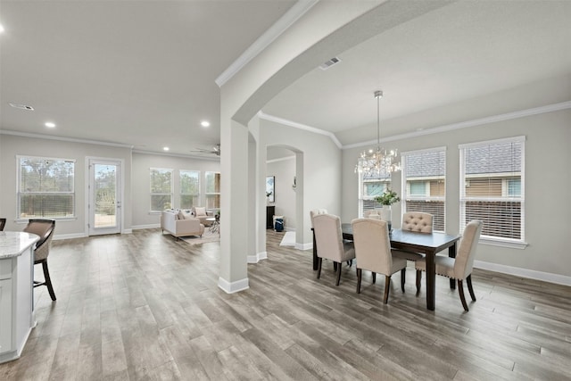 dining space with ornamental molding, ceiling fan with notable chandelier, and light wood-type flooring