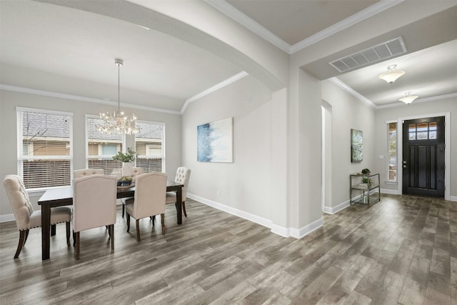 dining room with crown molding, hardwood / wood-style flooring, plenty of natural light, and an inviting chandelier