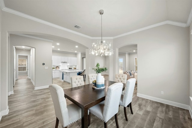 259 N Sage Holw, Dripping Springs, TX 78620 - dining area with arched walkways, light wood-style floors, baseboards, a chandelier, and ornamental molding