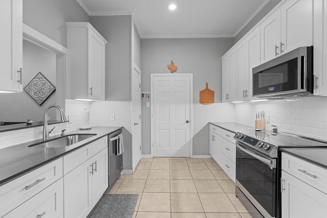 kitchen featuring sink, light tile patterned floors, crown molding, white cabinetry, and stainless steel appliances