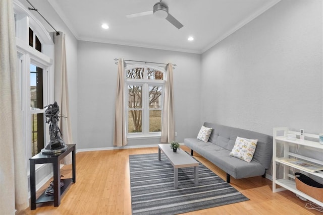 living area with ceiling fan, ornamental molding, and light wood-type flooring