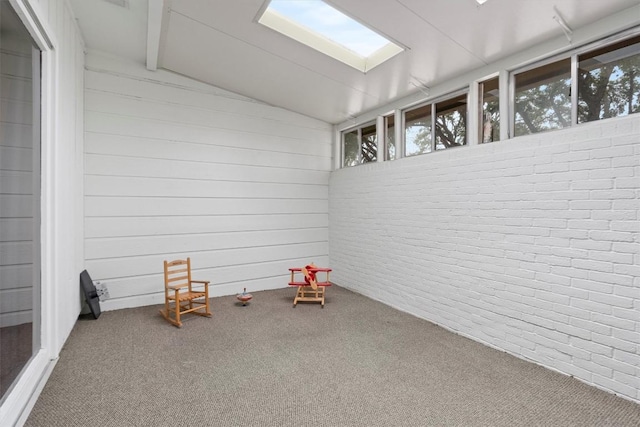 interior space with lofted ceiling with beams, brick wall, carpet flooring, and wood walls