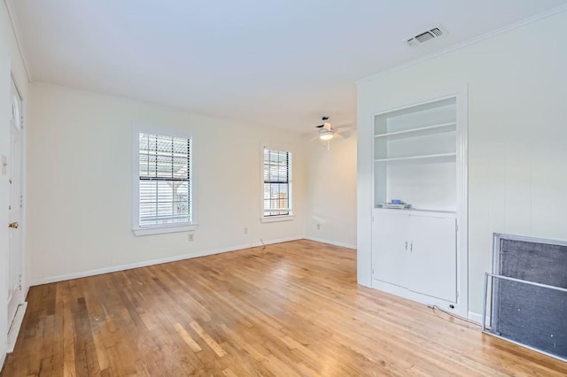 empty room featuring crown molding, ceiling fan, light hardwood / wood-style floors, and built in shelves