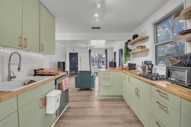 kitchen with sink, wooden counters, green cabinets, black gas stovetop, and stainless steel dishwasher