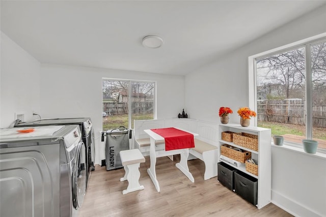 laundry area with washing machine and clothes dryer, a wealth of natural light, and light wood-type flooring