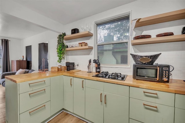 kitchen featuring tasteful backsplash, wooden counters, green cabinets, and black appliances