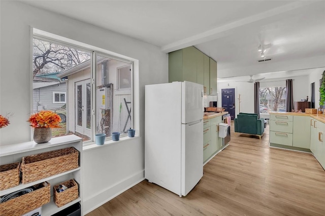 kitchen featuring ceiling fan, white fridge, green cabinets, and light wood-type flooring