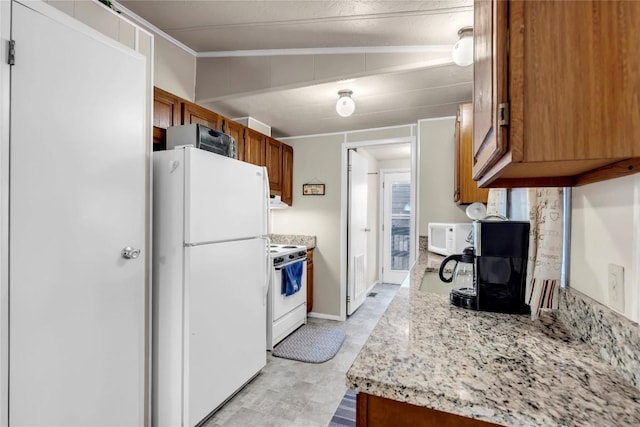 kitchen featuring vaulted ceiling, light stone counters, and white appliances