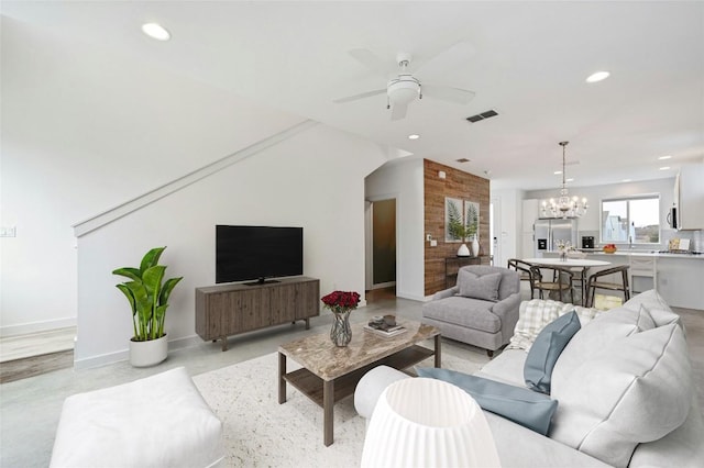 living room with visible vents, ceiling fan with notable chandelier, recessed lighting, baseboards, and concrete flooring