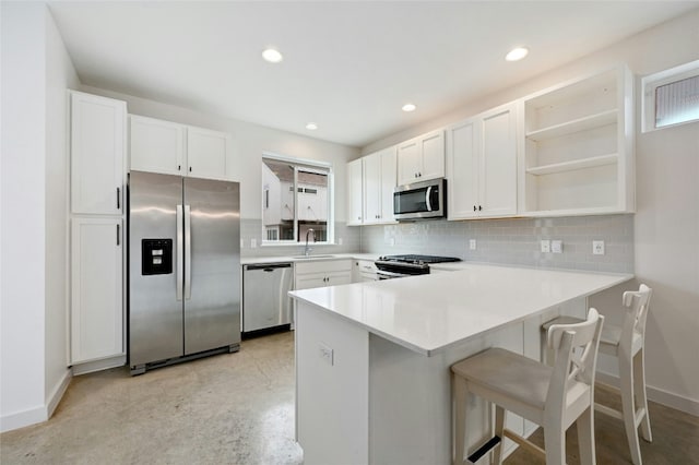 kitchen with a peninsula, open shelves, tasteful backsplash, and appliances with stainless steel finishes