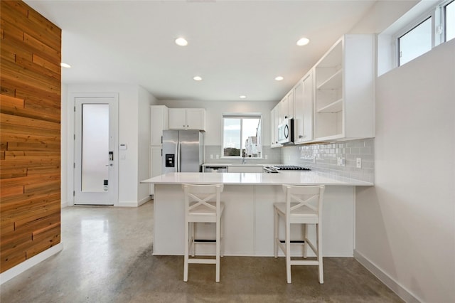 kitchen featuring open shelves, stainless steel appliances, concrete floors, a peninsula, and decorative backsplash